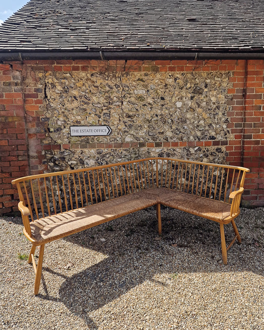 1950s Arno Lambrecht corner bench with rush seating in vintage workshop setting, mid century wooden L-shaped bench detail