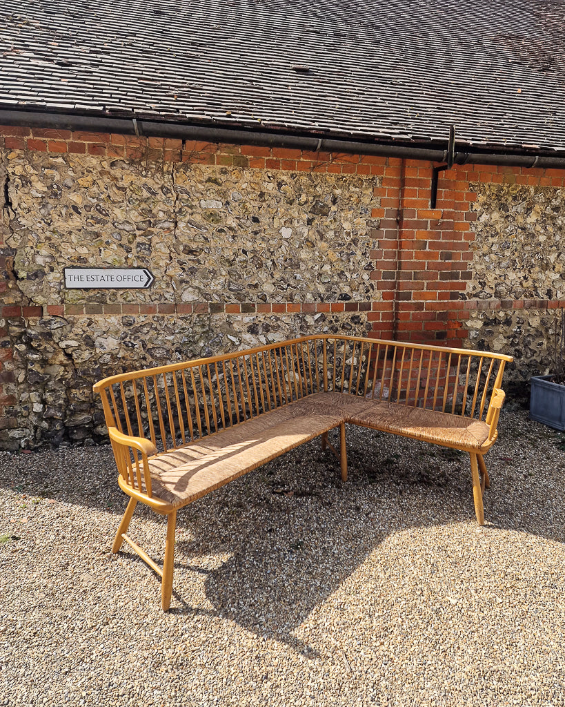 1950s Arno Lambrecht corner bench with rush seating in vintage workshop setting, mid century wooden L-shaped bench detail
