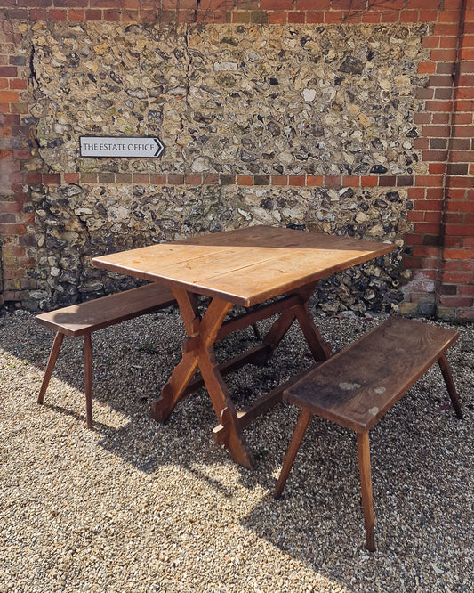 German solid oak dining table with three plank top and trestle base, paired with rustic wooden benches in farmhouse setting