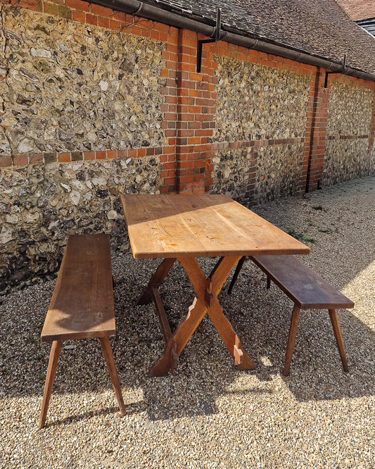German solid oak dining table with three plank top and trestle base, paired with rustic wooden benches in farmhouse setting