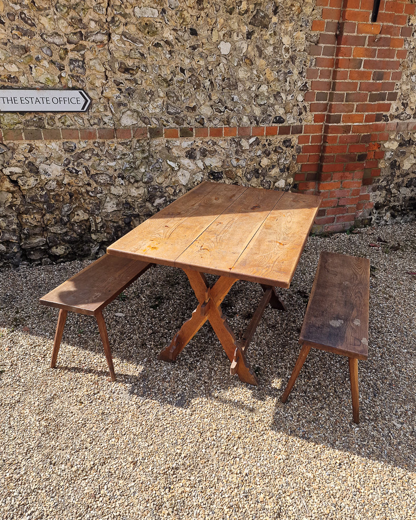German solid oak dining table with three plank top and trestle base, paired with rustic wooden benches in farmhouse setting