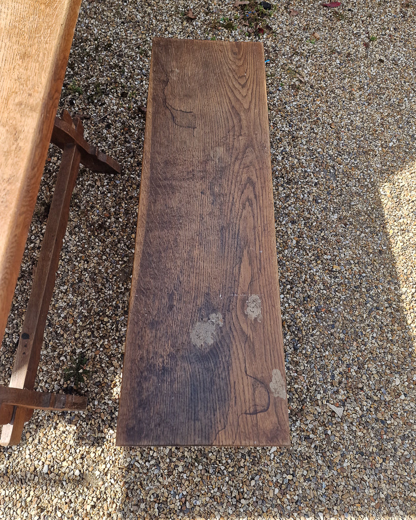 German solid oak dining table with three plank top and trestle base, paired with rustic wooden benches in farmhouse setting