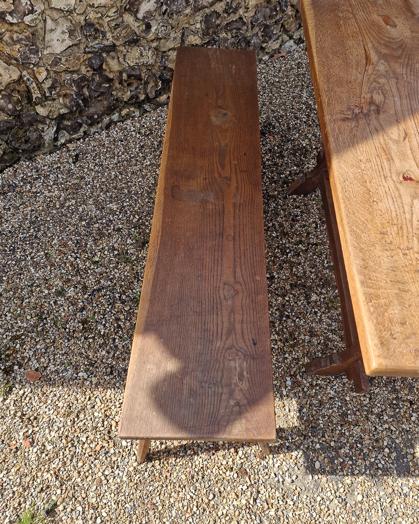 German solid oak dining table with three plank top and trestle base, paired with rustic wooden benches in farmhouse setting