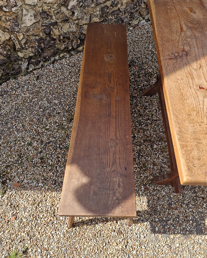 German solid oak dining table with three plank top and trestle base, paired with rustic wooden benches in farmhouse setting