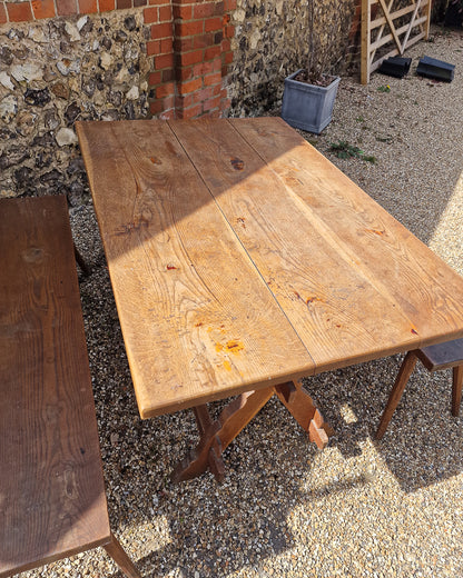 German solid oak dining table with three plank top and trestle base, paired with rustic wooden benches in farmhouse setting