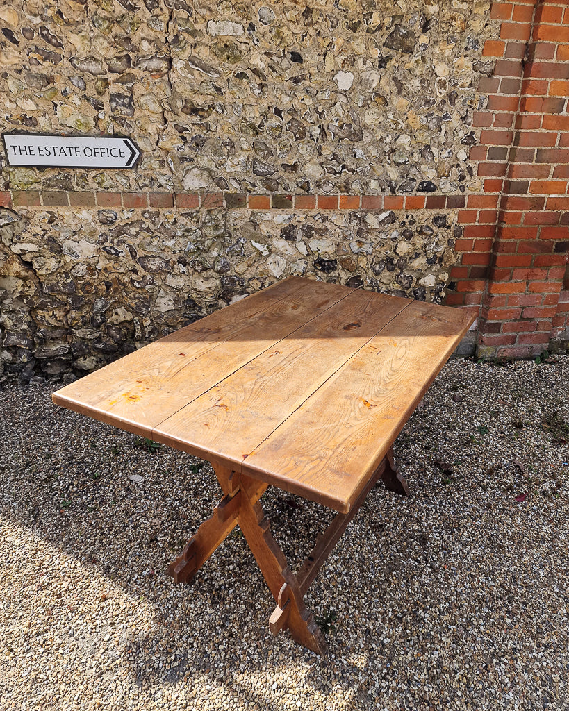 German solid oak dining table with three plank top and trestle base, paired with rustic wooden benches in farmhouse setting