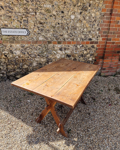 German solid oak dining table with three plank top and trestle base, paired with rustic wooden benches in farmhouse setting