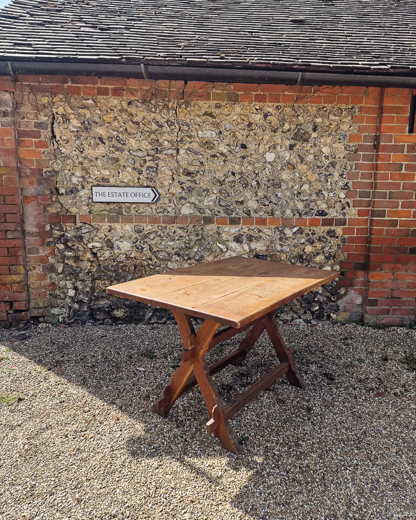 German solid oak dining table with three plank top and trestle base, paired with rustic wooden benches in farmhouse setting