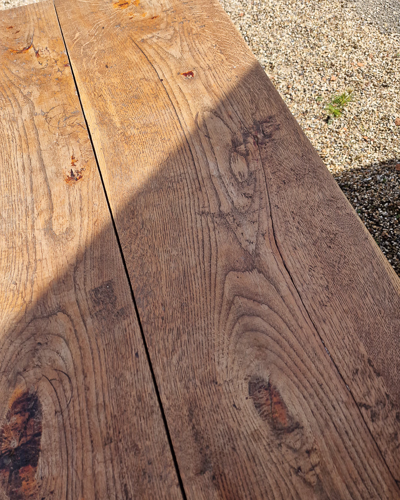 German solid oak dining table with three plank top and trestle base, paired with rustic wooden benches in farmhouse setting