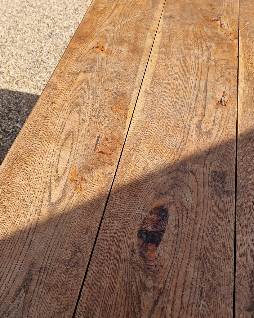 German solid oak dining table with three plank top and trestle base, paired with rustic wooden benches in farmhouse setting
