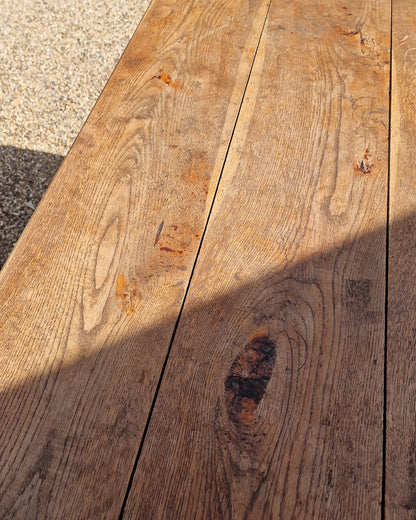 German solid oak dining table with three plank top and trestle base, paired with rustic wooden benches in farmhouse setting