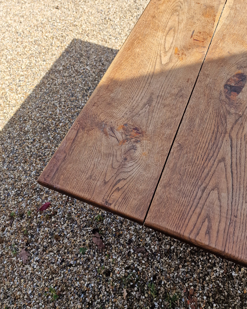 German solid oak dining table with three plank top and trestle base, paired with rustic wooden benches in farmhouse setting