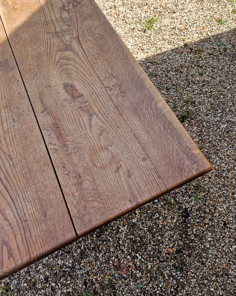 German solid oak dining table with three plank top and trestle base, paired with rustic wooden benches in farmhouse setting